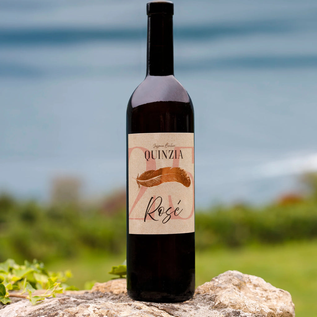 Flasche Quinzia Rosé auf einem Stein vor einem Rebberg und dem Walensee.
